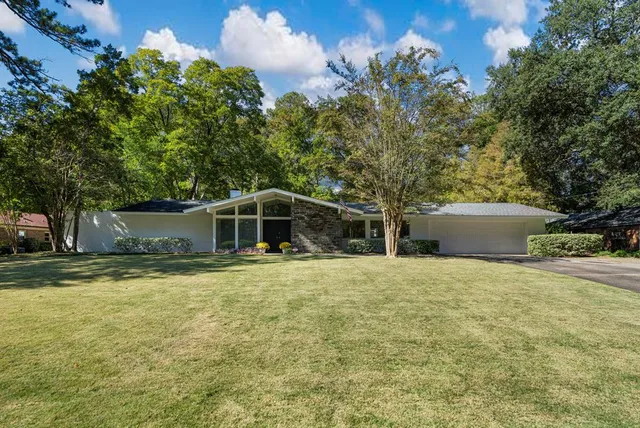 a front view of a house with a garden and trees
