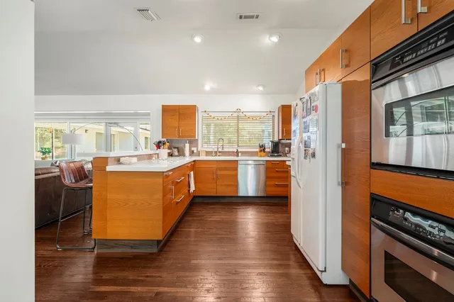 a kitchen with stainless steel appliances granite countertop a refrigerator a oven a sink dishwasher and wooden cabinets with wooden floor