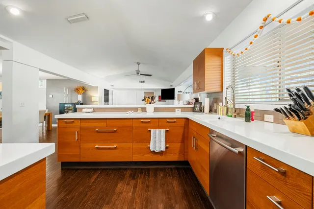 a kitchen with stainless steel appliances a sink dishwasher and wooden cabinets with wooden floor