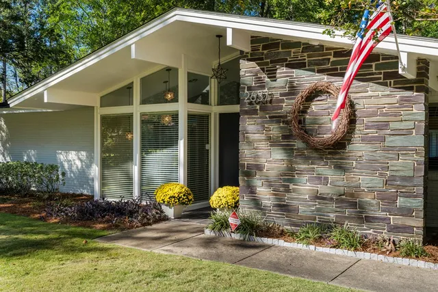 a view of a wooden house with a small yard and potted plants
