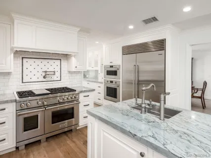 a kitchen with granite countertop a stove a sink and a refrigerator
