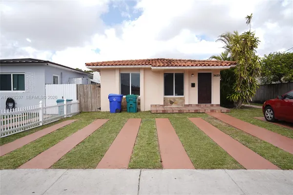 a front view of a house with a yard and potted plants