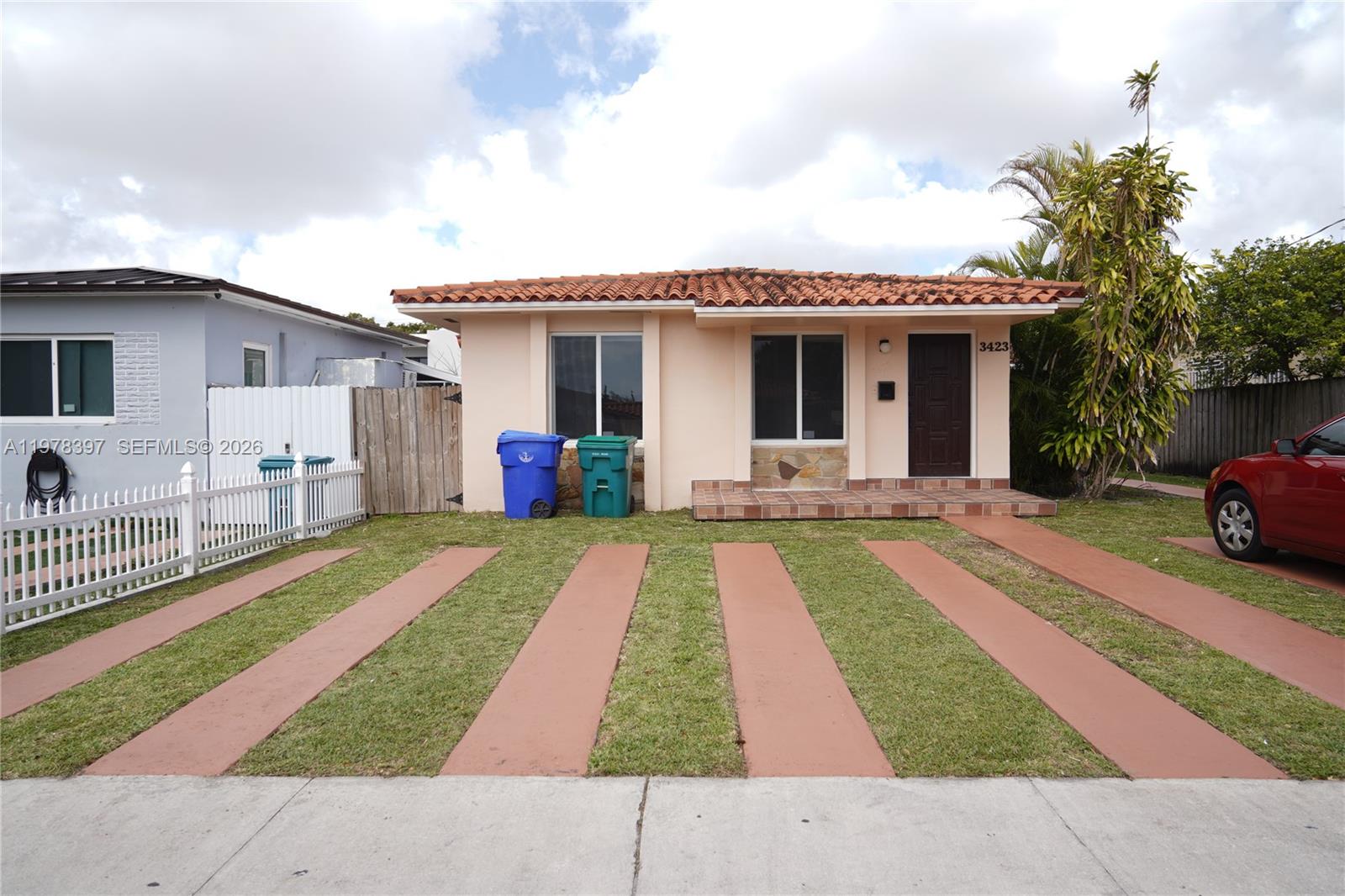 a front view of a house with a yard and potted plants