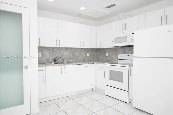 a kitchen with white cabinets and white appliances