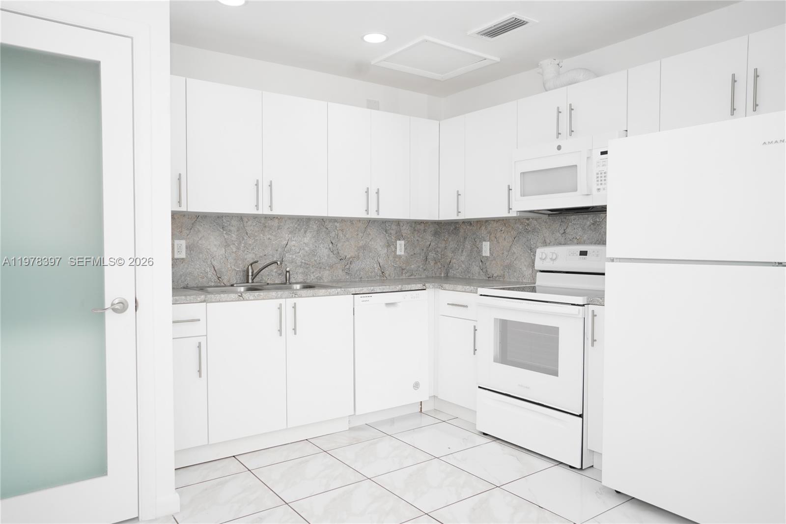 3423 Southwest 3rd Street, Unit 1 Miami, FL 33135 - Photo 3 of 18 a kitchen with white cabinets and white appliances