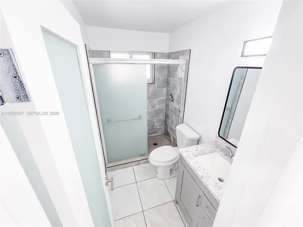 a bathroom with a granite countertop sink toilet and shower