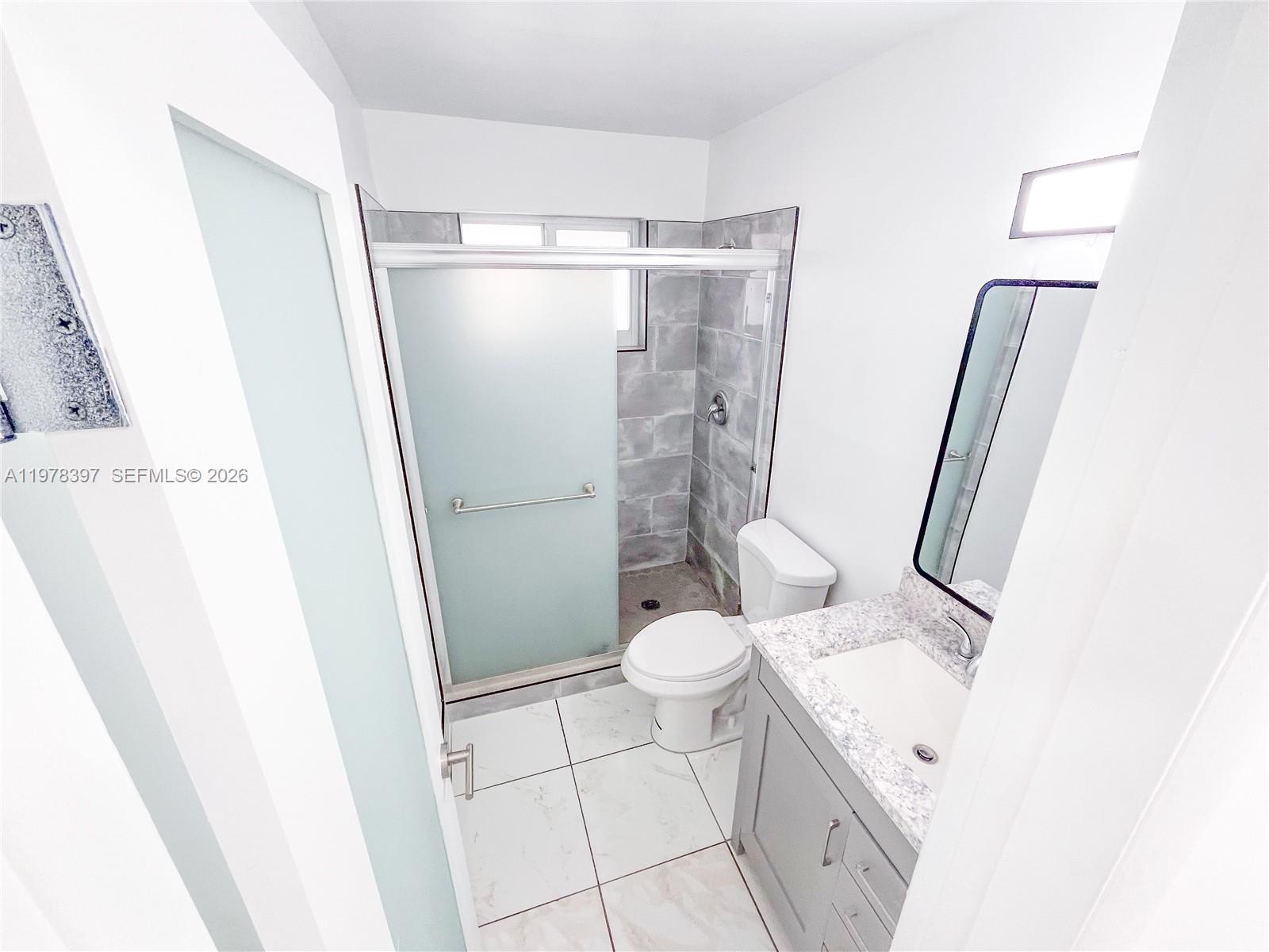 3423 Southwest 3rd Street, Unit 1 Miami, FL 33135 - Photo 10 of 18 a bathroom with a granite countertop sink toilet and shower