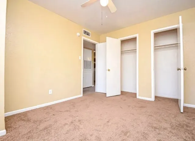 a view of an empty room with a chandelier fan