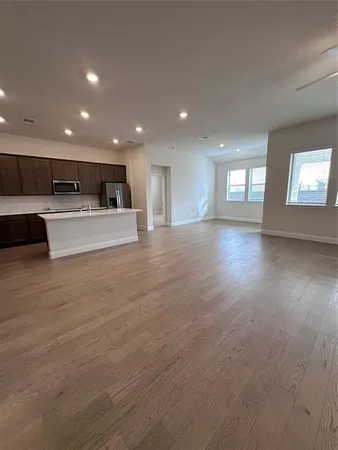 a view of kitchen with kitchen island microwave and wooden floor