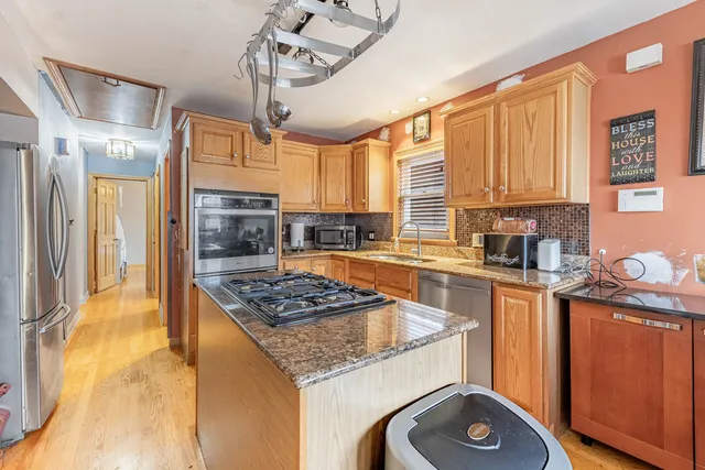 a kitchen with stainless steel appliances granite countertop a stove a sink dishwasher and refrigerator with wooden floor