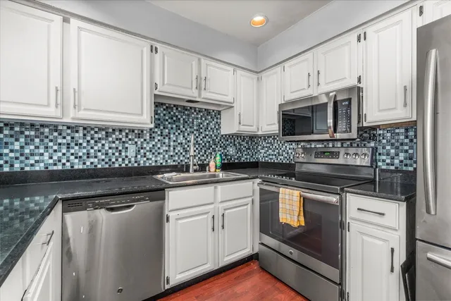 a kitchen with granite countertop white cabinets and stainless steel appliances