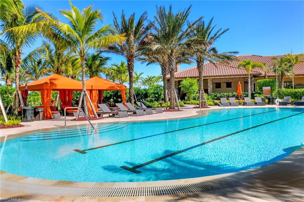 9366 Pocida Court, Unit 202 Naples, FL 34119 - Photo 32 of 44 a view of a swimming pool with a lawn chairs under an umbrella