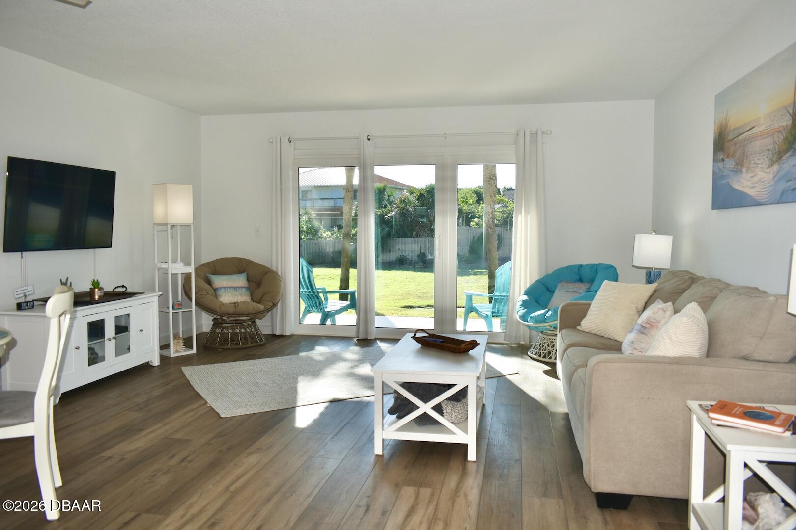 4790 South Atlantic Avenue, Unit F602 Ponce Inlet, FL 32127 - Photo 3 of 23 a living room with furniture a flat screen tv and a floor to ceiling window