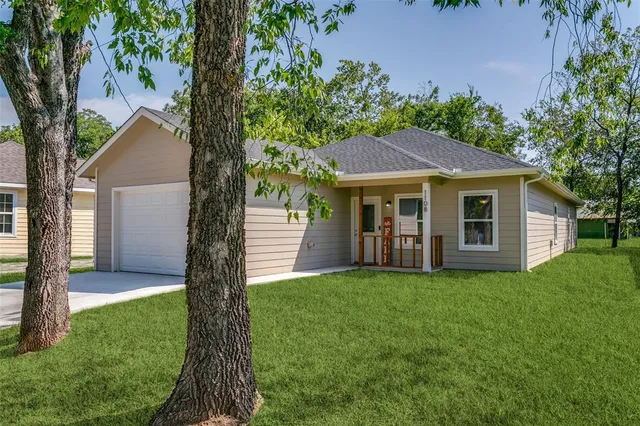 a front view of a house with a yard and trees