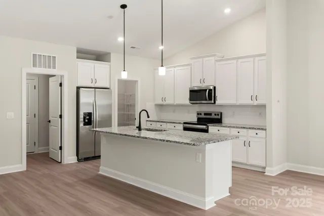 a kitchen with stainless steel appliances granite countertop a sink a stove a refrigerator and a microwave