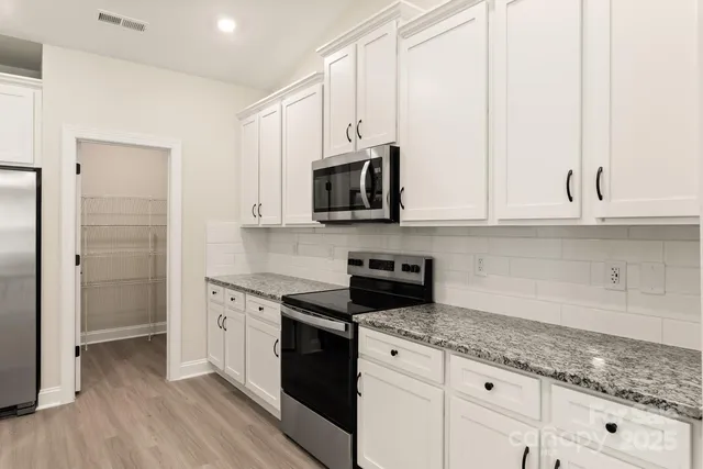 a kitchen with granite countertop white cabinets and stainless steel appliances