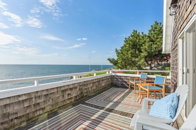 a balcony with wooden floor and outdoor seating