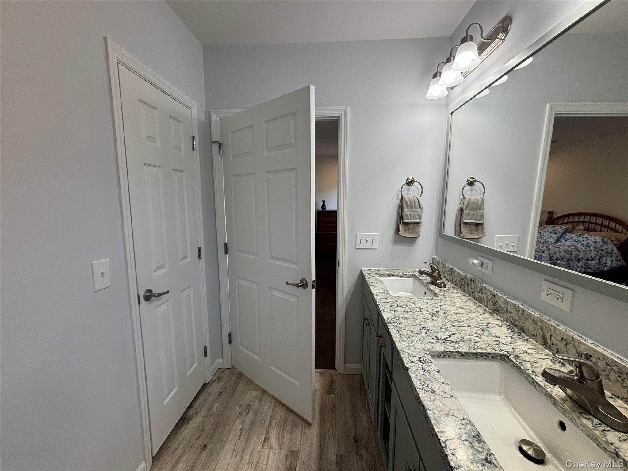 1661 Old Country Road, Unit 563 Riverhead, NY 11901 - Photo 33 of 43 a bathroom with a granite countertop double vanity sink a mirror and shower