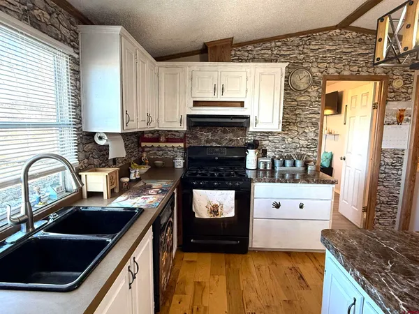 a kitchen with granite countertop a stove sink and cabinets