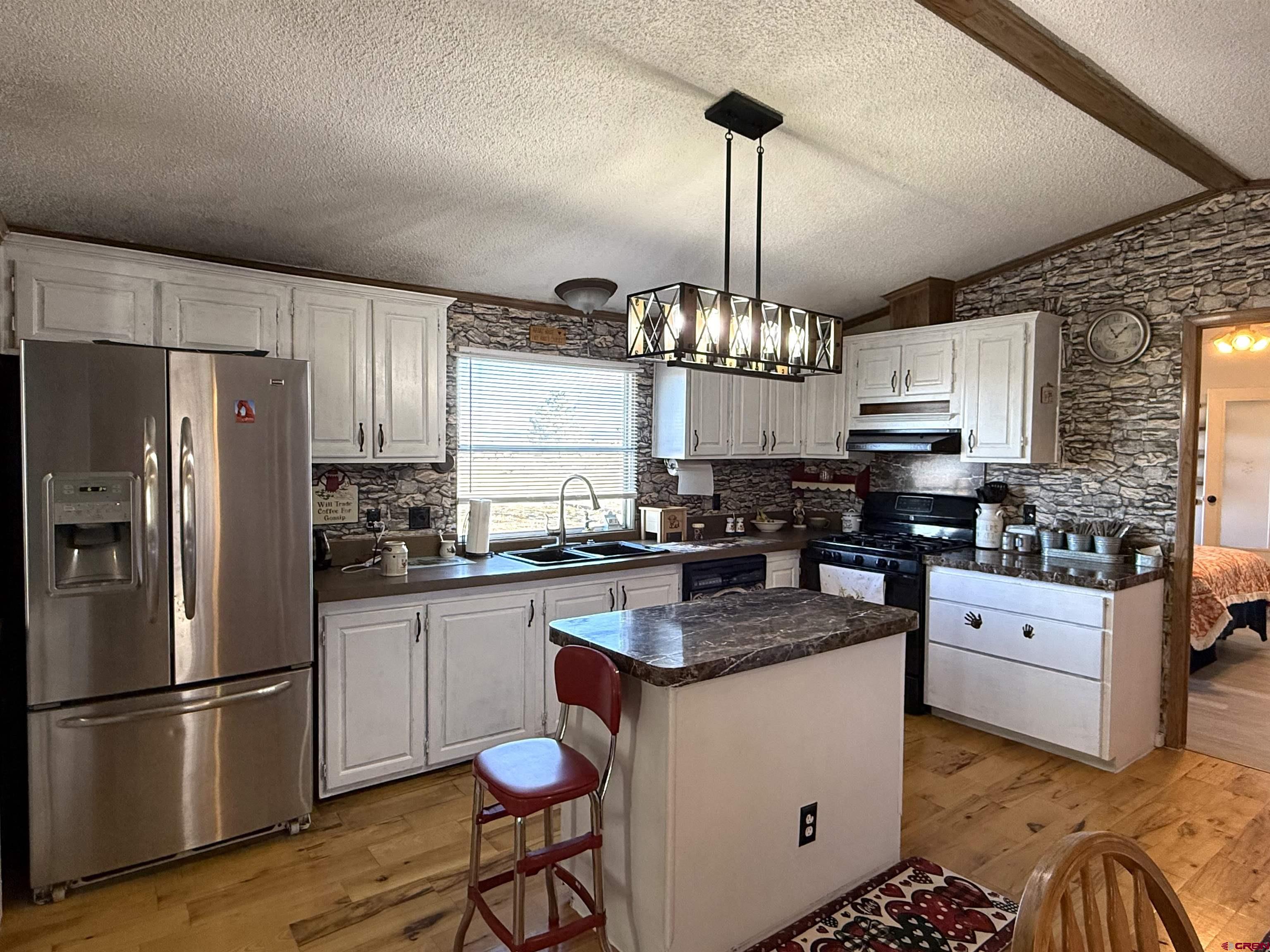 15546 Rd BB Pleasant View, CO 81331 - Photo 9 of 29 a kitchen with granite countertop a refrigerator a stove a sink cabinets and wooden floor
