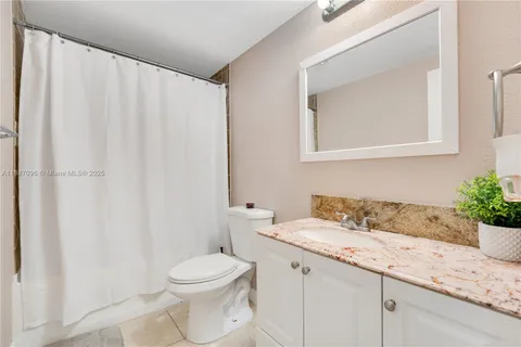 a bathroom with a granite countertop sink mirror vanity and toilet
