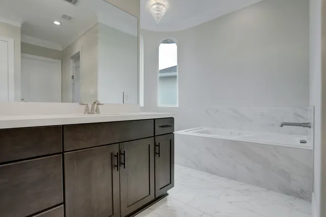 a bathroom with a bathtub sink vanity and mirror