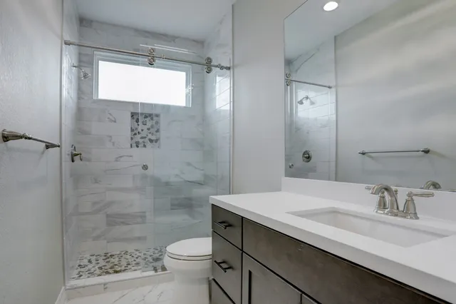 a bathroom with a sink a toilet and shower