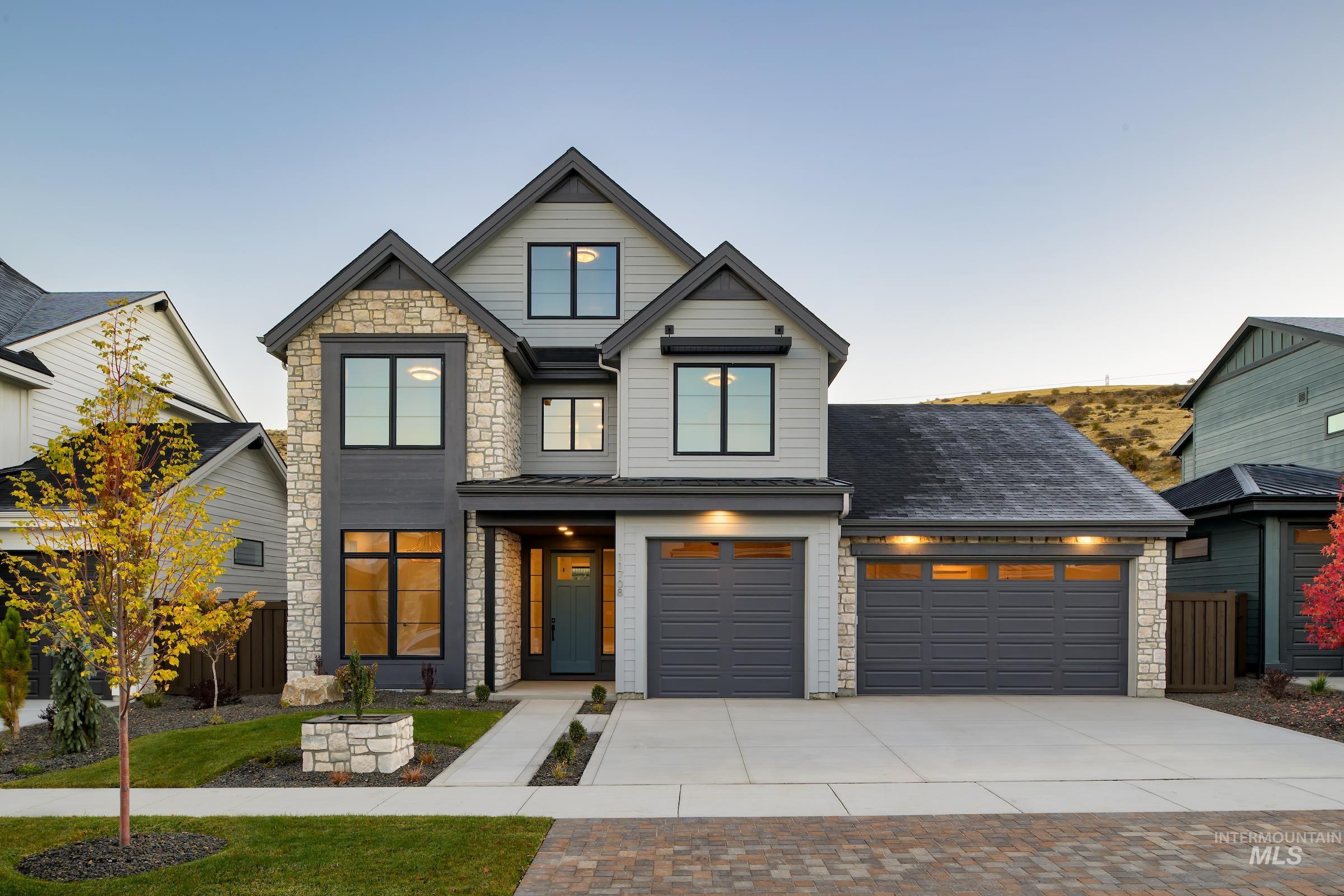 View of front of property featuring stone siding, driveway, and a garage