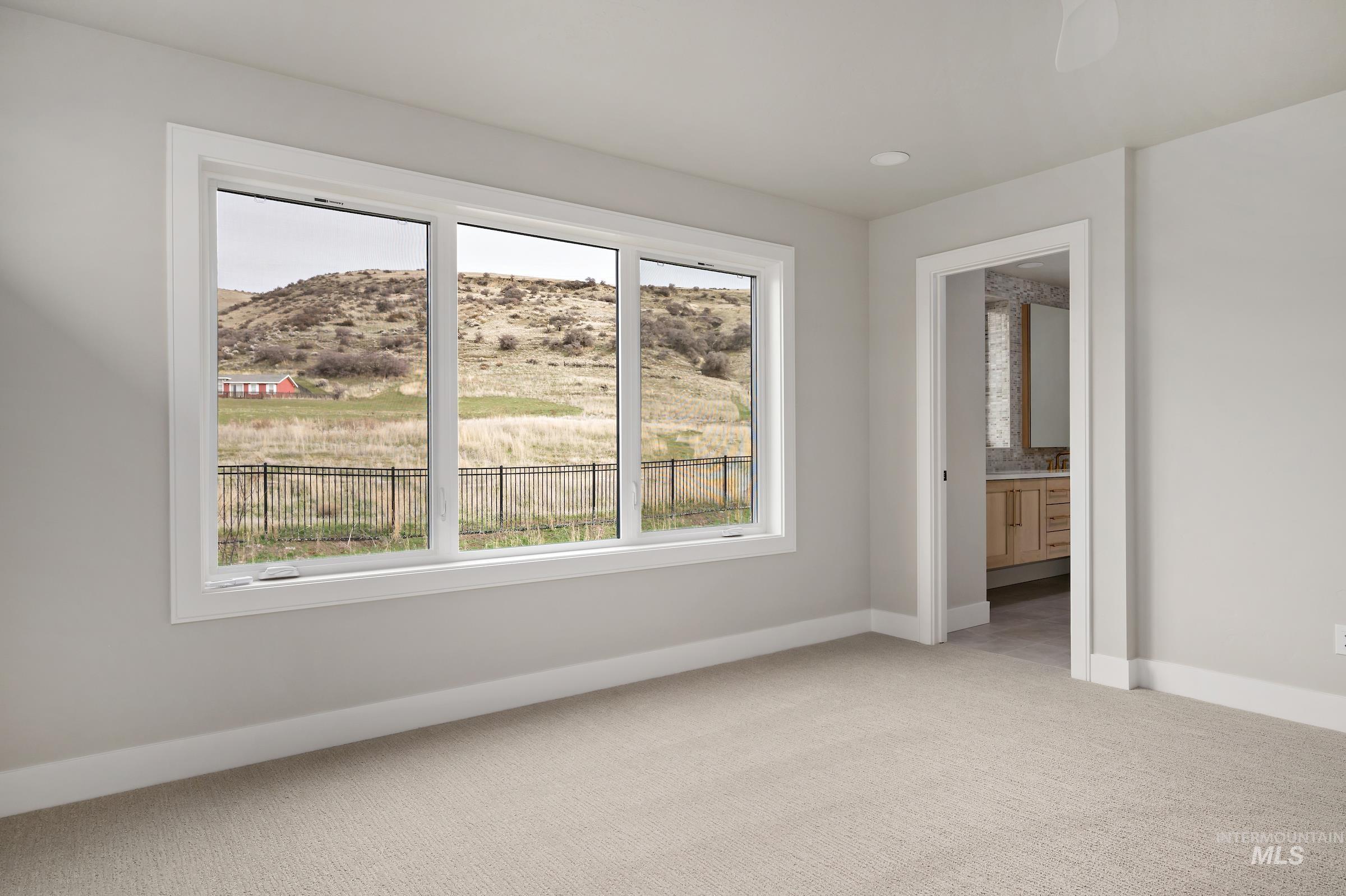 11708 North Rabbitbrush Way Boise, ID 83714 - Photo 17 of 33 Unfurnished bedroom with connected bathroom, light carpet, and a mountain view