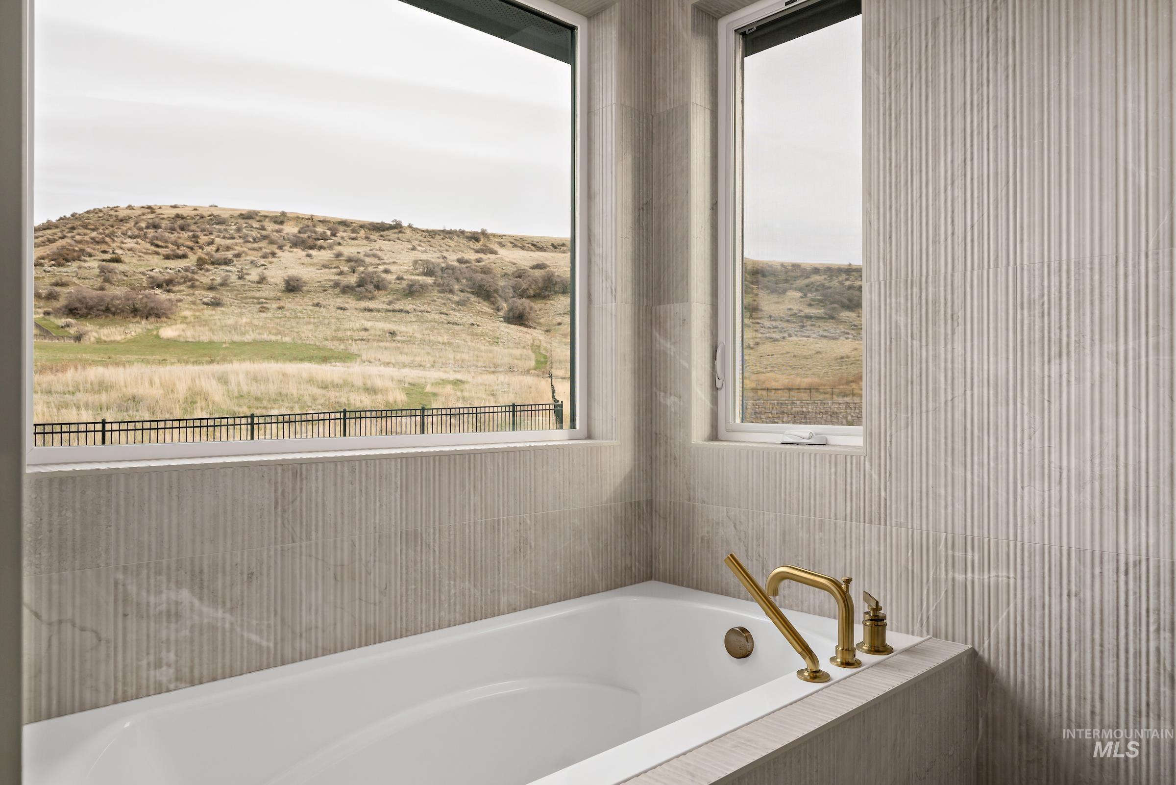 11708 North Rabbitbrush Way Boise, ID 83714 - Photo 19 of 33 Bathroom featuring a bath, a mountain view, and tile walls