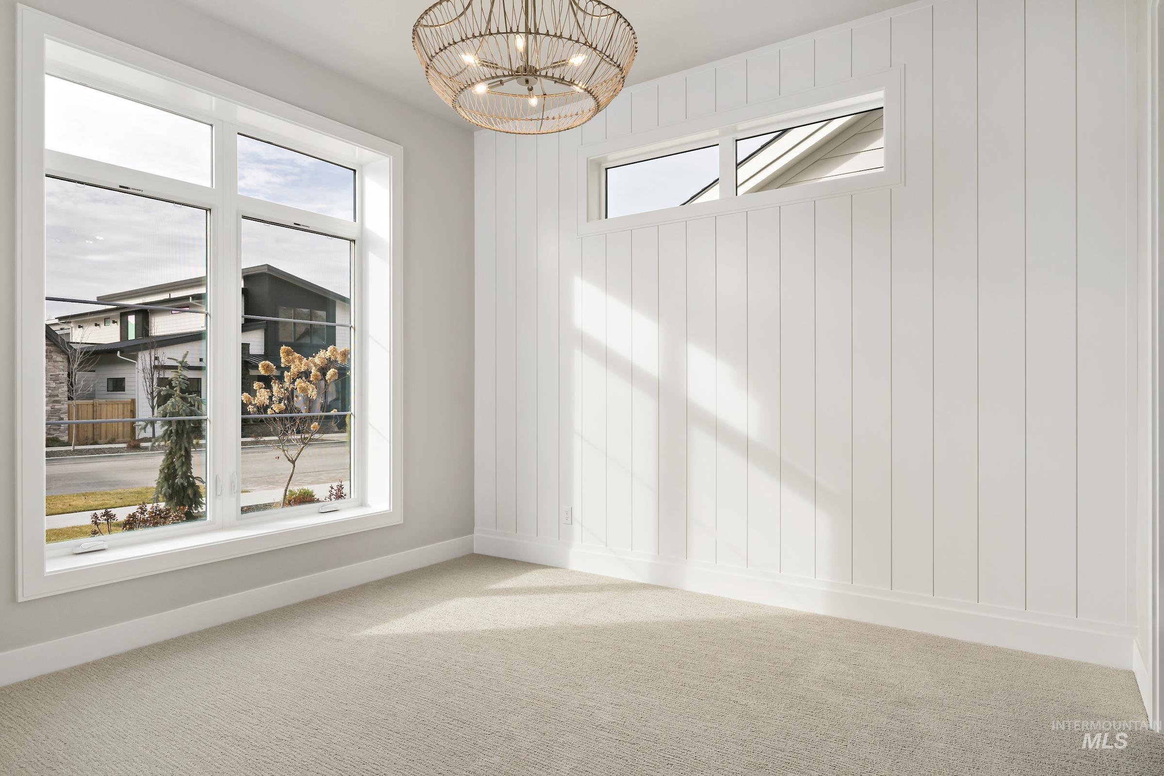 11708 North Rabbitbrush Way Boise, ID 83714 - Photo 6 of 33 Empty room featuring healthy amount of natural light, carpet, a chandelier, and wood walls