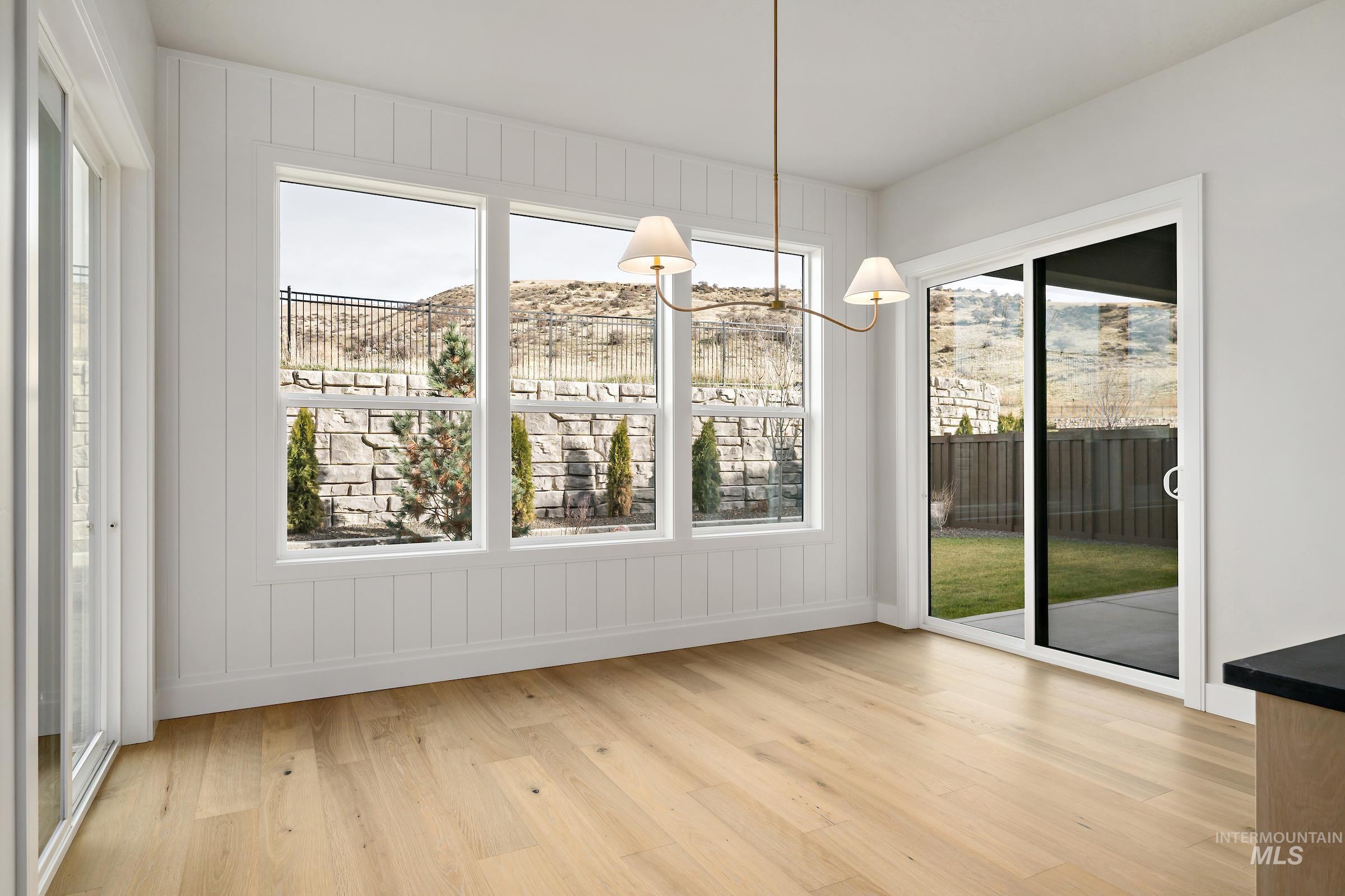 11708 North Rabbitbrush Way Boise, ID 83714 - Photo 10 of 33 Unfurnished dining area featuring light wood-style flooring, healthy amount of natural light, a mountain view, and a chandelier