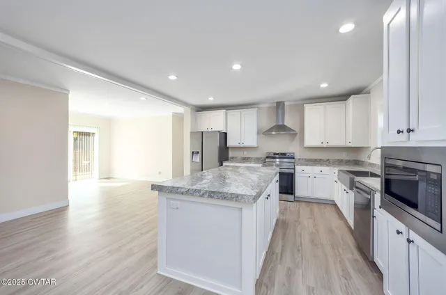 a large kitchen with granite countertop a large counter top stainless steel appliances and cabinets