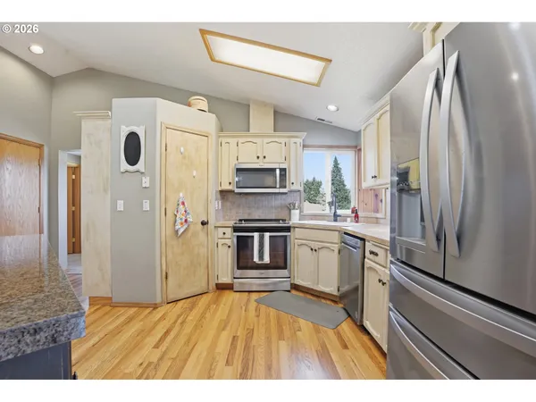 a kitchen with stainless steel appliances granite countertop a refrigerator a stove and a sink
