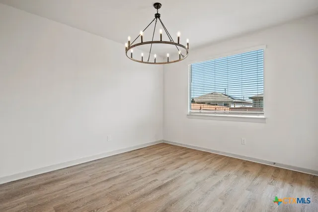 an empty room with wooden floor a ceiling fan and windows