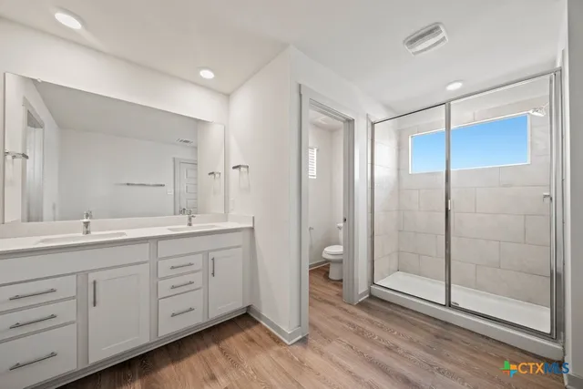 a spacious bathroom with a double vanity sink a mirror and a shower