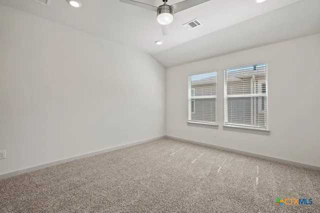 an empty room with windows and ceiling fan