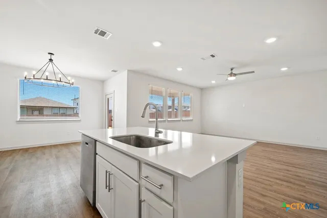 a kitchen with a sink dishwasher and a refrigerator with wooden floor