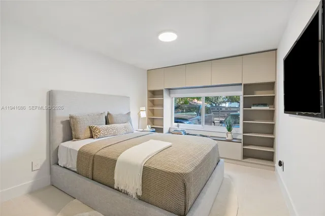 a bedroom with a large bed and a flat tv screen on dresser