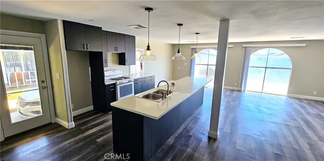 a kitchen with stainless steel appliances a refrigerator a sink dishwasher a stove with wooden floor and cabinets next to a window