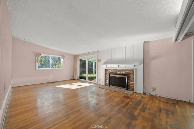 an empty room with windows fireplace and wooden floor