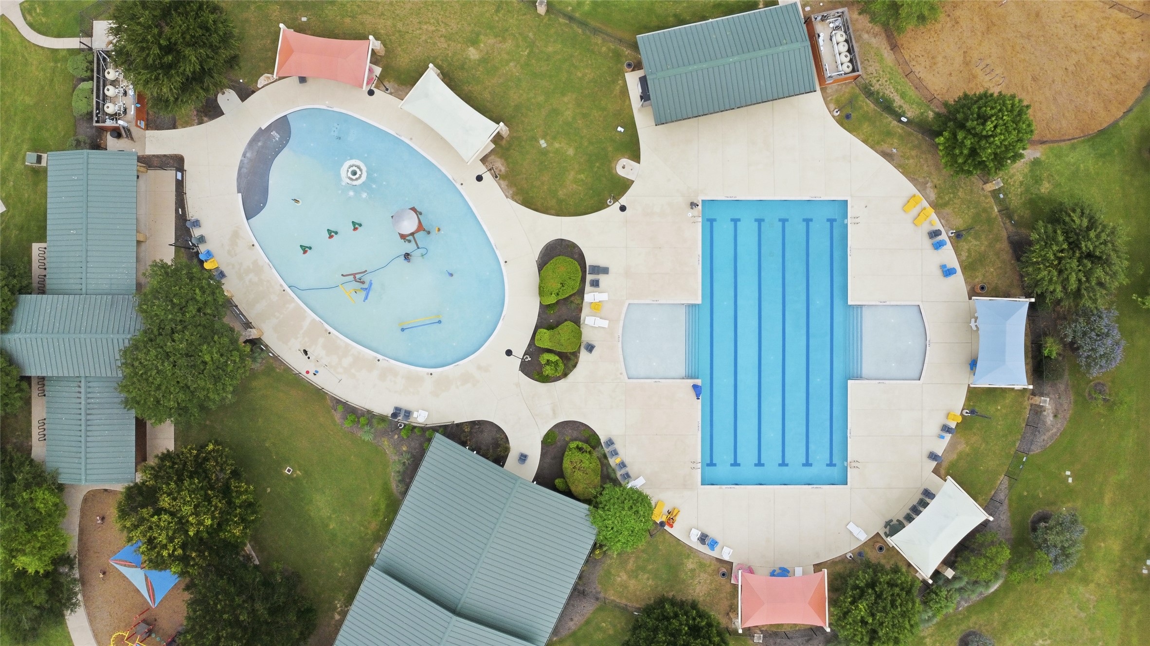 486 Pond View Pass Buda, TX 78610 - Photo 39 of 39 Recreational aquatic complex featuring a multi-lane lap pool, an irregularly shaped leisure pool with water features, extensive concrete decking, and multiple covered shade structures