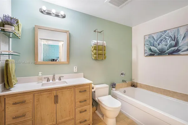 a bathroom with a toilet a sink a mirror a bathtub and vanity