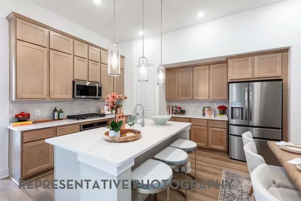 a kitchen with stainless steel appliances granite countertop a stove a refrigerator a sink dishwasher a dining table and chairs with wooden floor