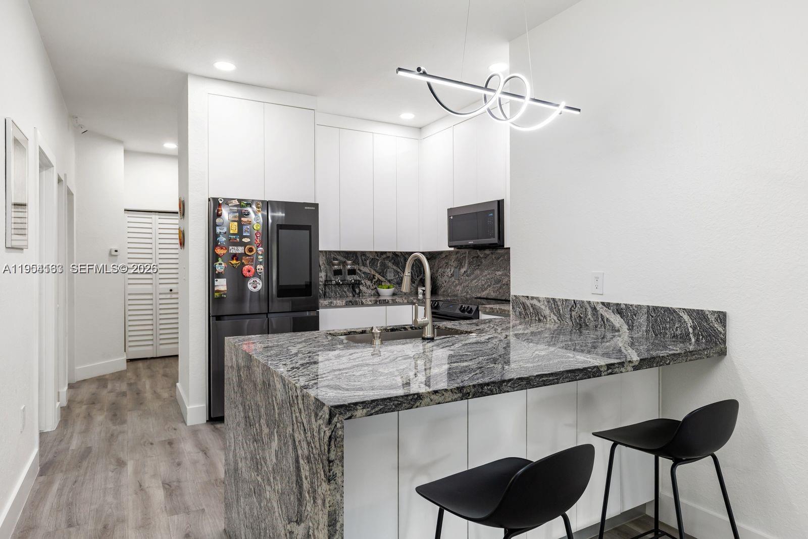 a kitchen with stainless steel appliances granite countertop a sink and a refrigerator