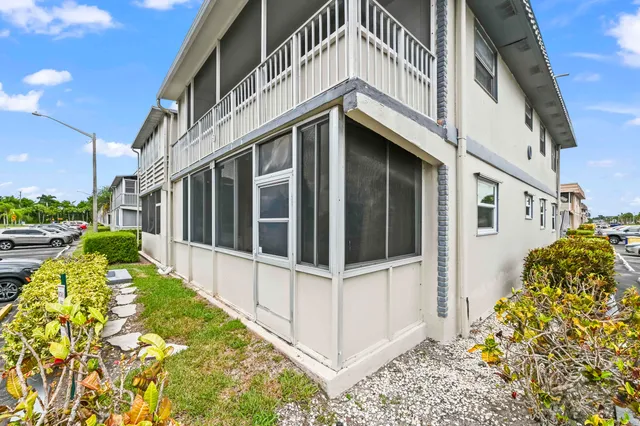 a view of a white house with a large window and flower plants