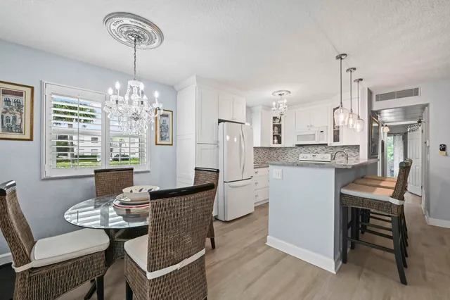 a dining room with furniture a chandelier and kitchen view