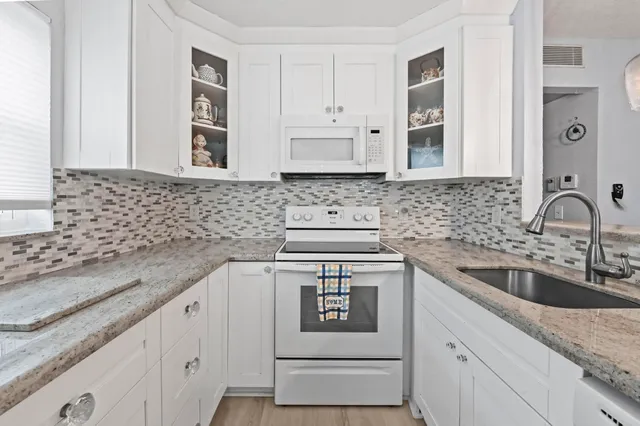 a kitchen with granite countertop a sink stove and cabinets