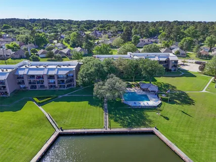 a view of a swimming pool with a yard and large trees