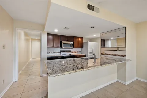 a large kitchen with kitchen island granite countertop a large counter top and wooden cabinets